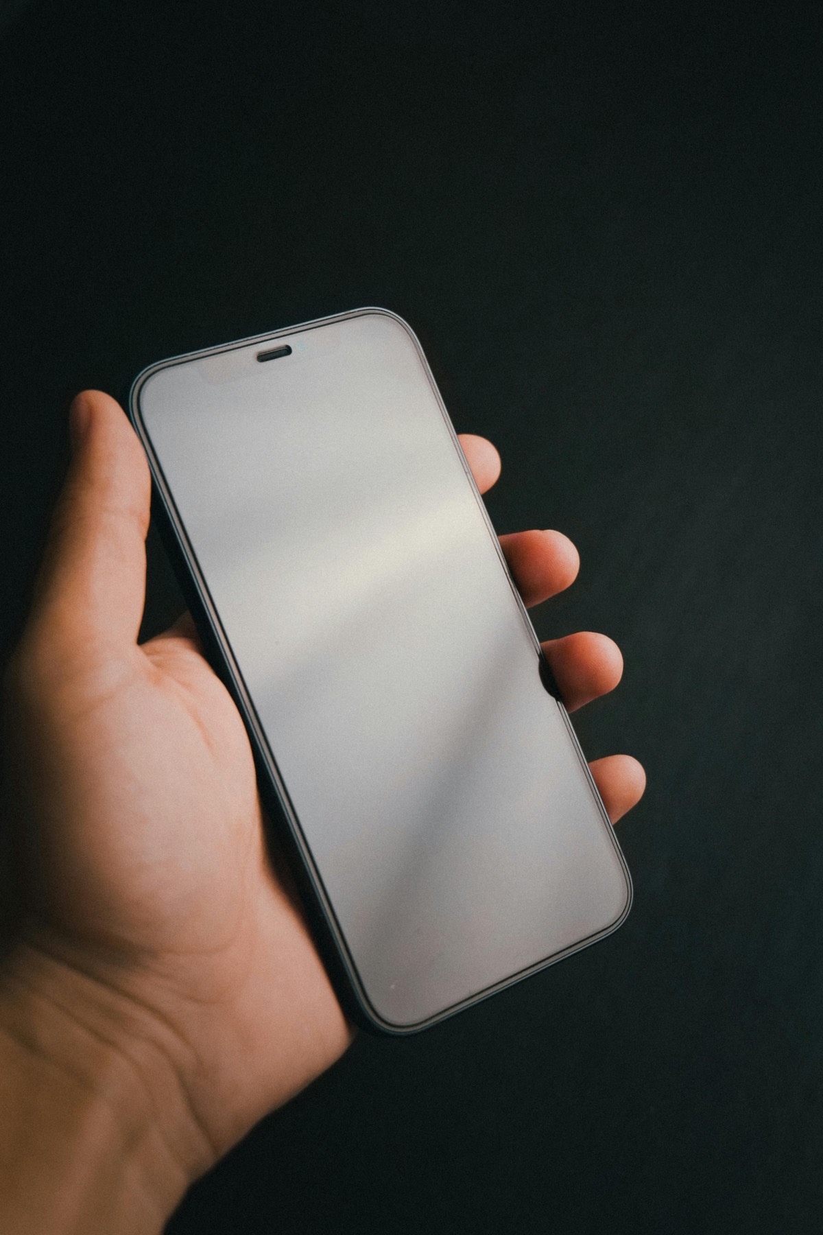 Main tenant un smartphone dans une ambiance sombre pour illustrer l'usage mobile de Groov'It